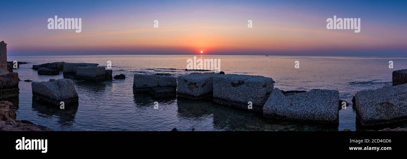 Splendida vista panoramica del tramonto sul Mar Mediterraneo in Sicilia, grandi rocce in primo piano Foto Stock