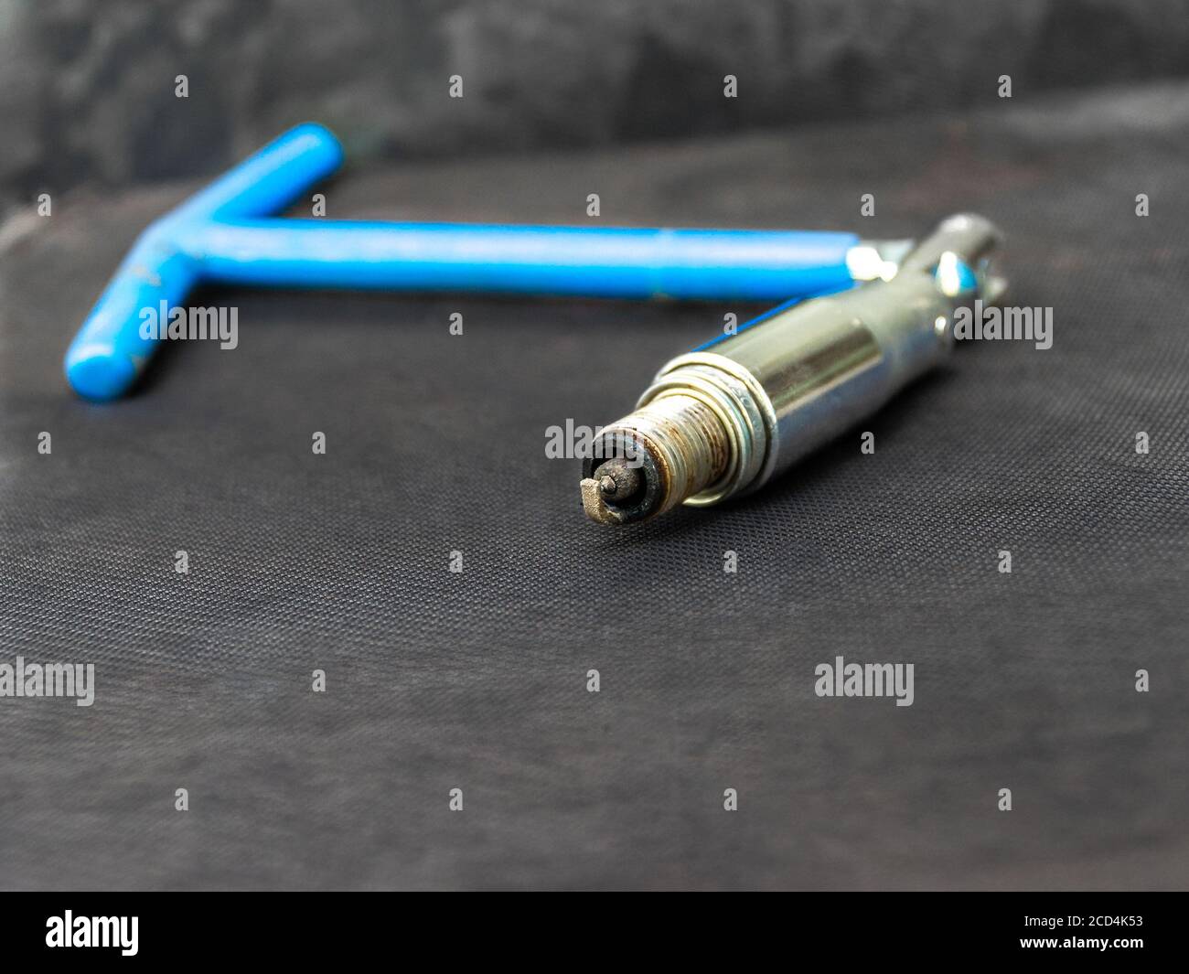 vecchia candela rivestita in carbonio con chiave blu incernierata per candele di accensione di un motore a combustione interna necessario alla stazione di servizio Foto Stock