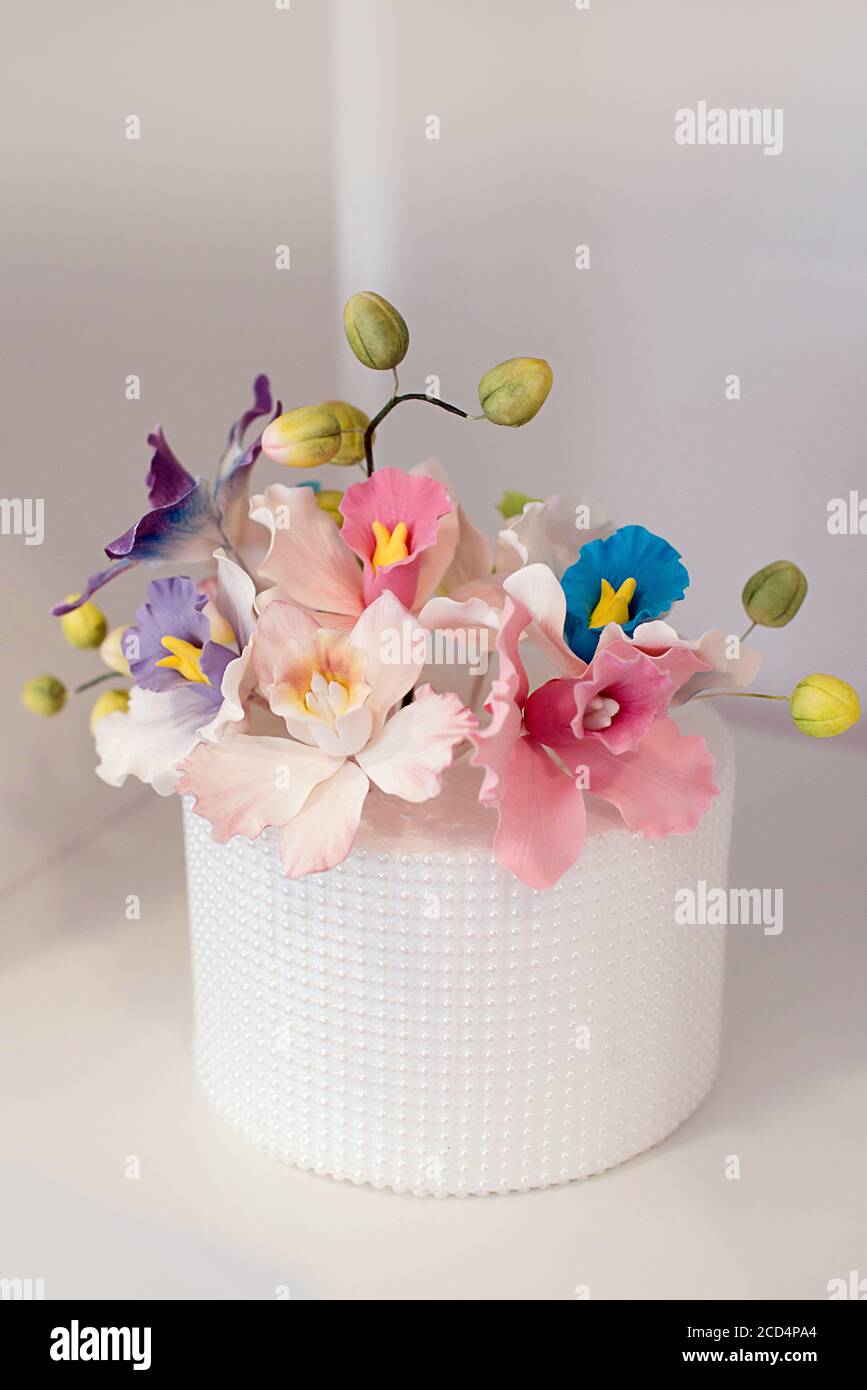Elegante decorazione floreale per una torta nuziale, coperta di glassa reale e perle di zucchero posizionate simmetricamente, con rose in pasta alimentare di zucchero Foto Stock