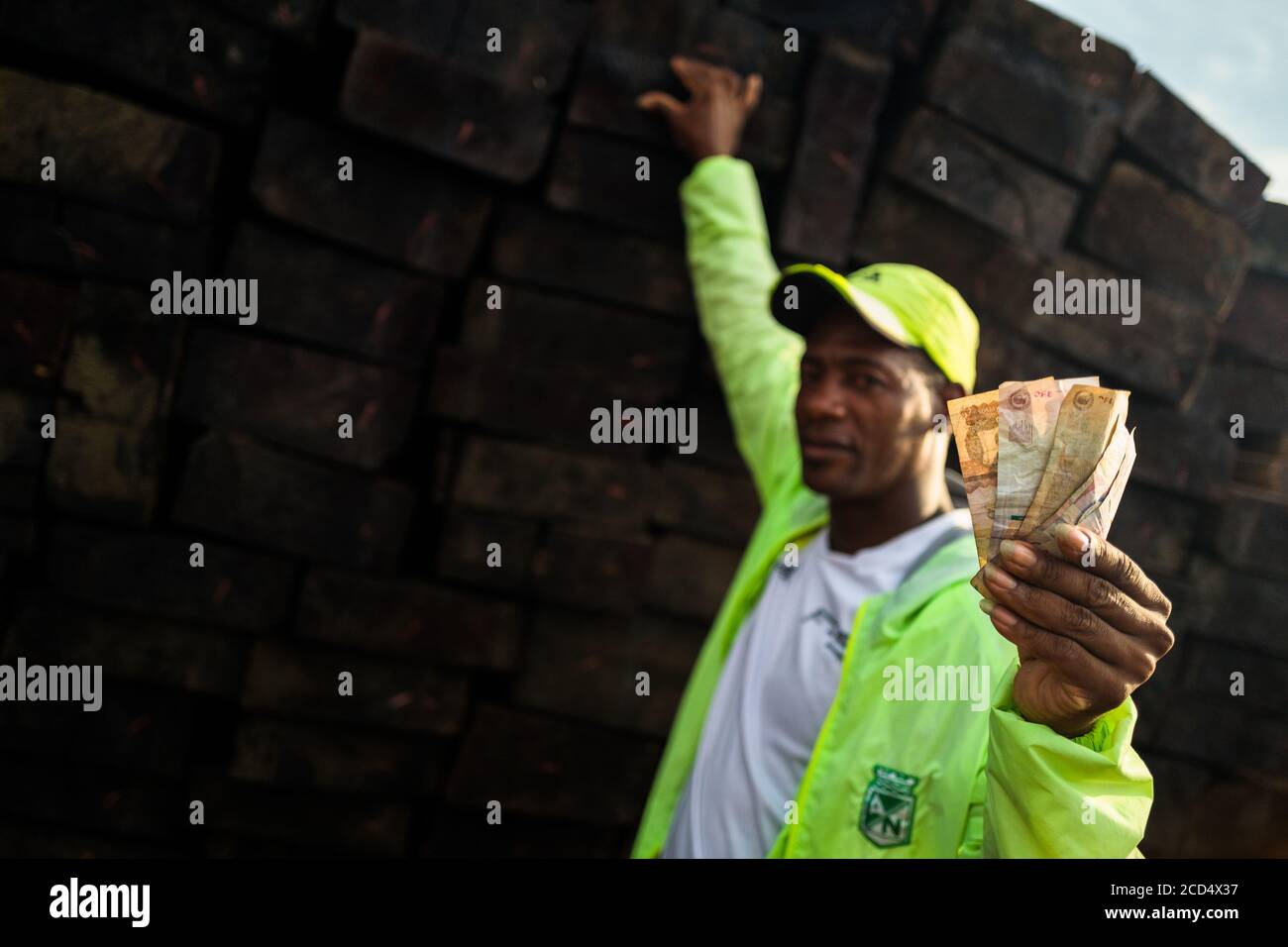 Un rivenditore di legno colombiano detiene banconote mentre vende legname segato grezzo, estratto dalla foresta pluviale del Pacifico, nel porto di Turbo, Colombia. Foto Stock
