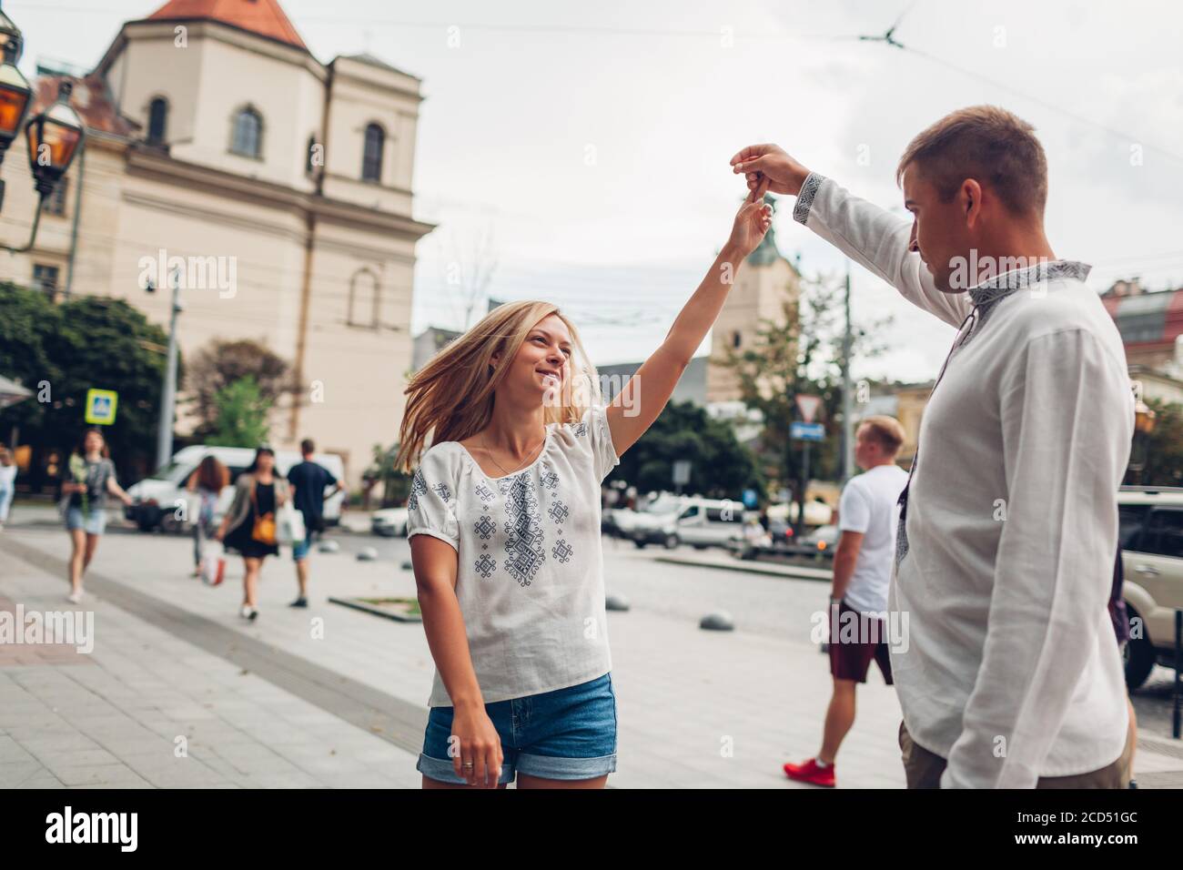 I giovani innamorati camminano nella vecchia città di Lviv indossando camicie tradizionali ucraine. Coppia danze divertendosi Foto Stock