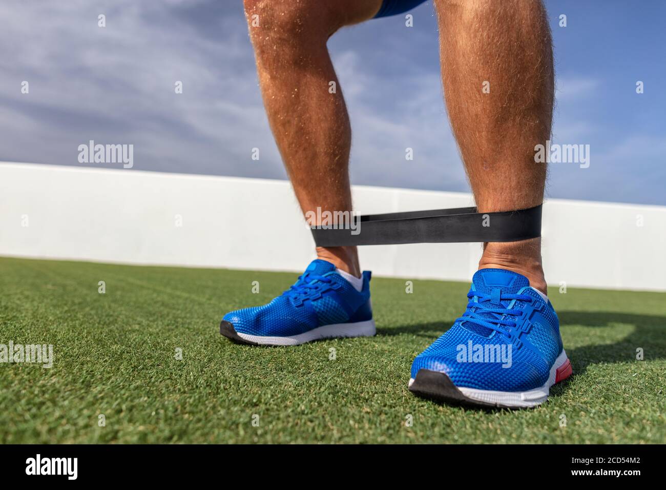 Resistance band allenamento uomo in palestra allenamento muscoli polpaccio con fasce in gomma. Esercizi di peso corporeo all'aperto nel parco Foto Stock