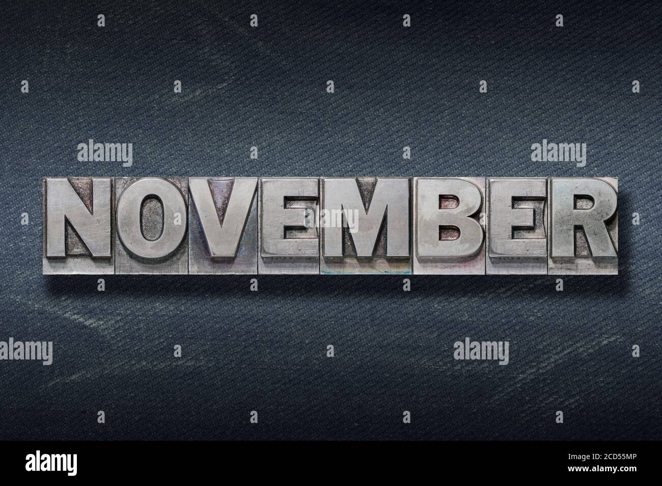 Parola di novembre realizzata con stampa letterpress metallizzata su sfondo jeans scuro Foto Stock
