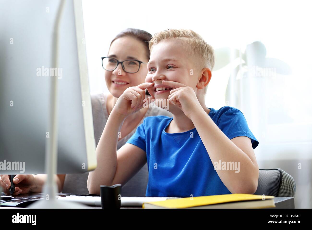 Scuola di casa, formazione online. La mamma aiuta il bambino a imparare online. Foto Stock