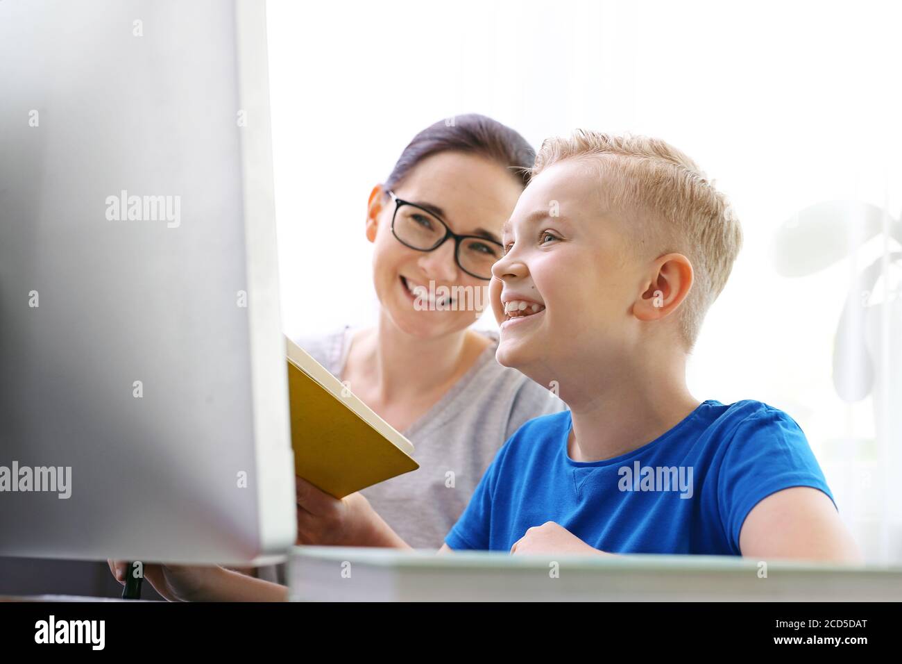 Scuola di casa, formazione online. La mamma aiuta il bambino a imparare online. Foto Stock