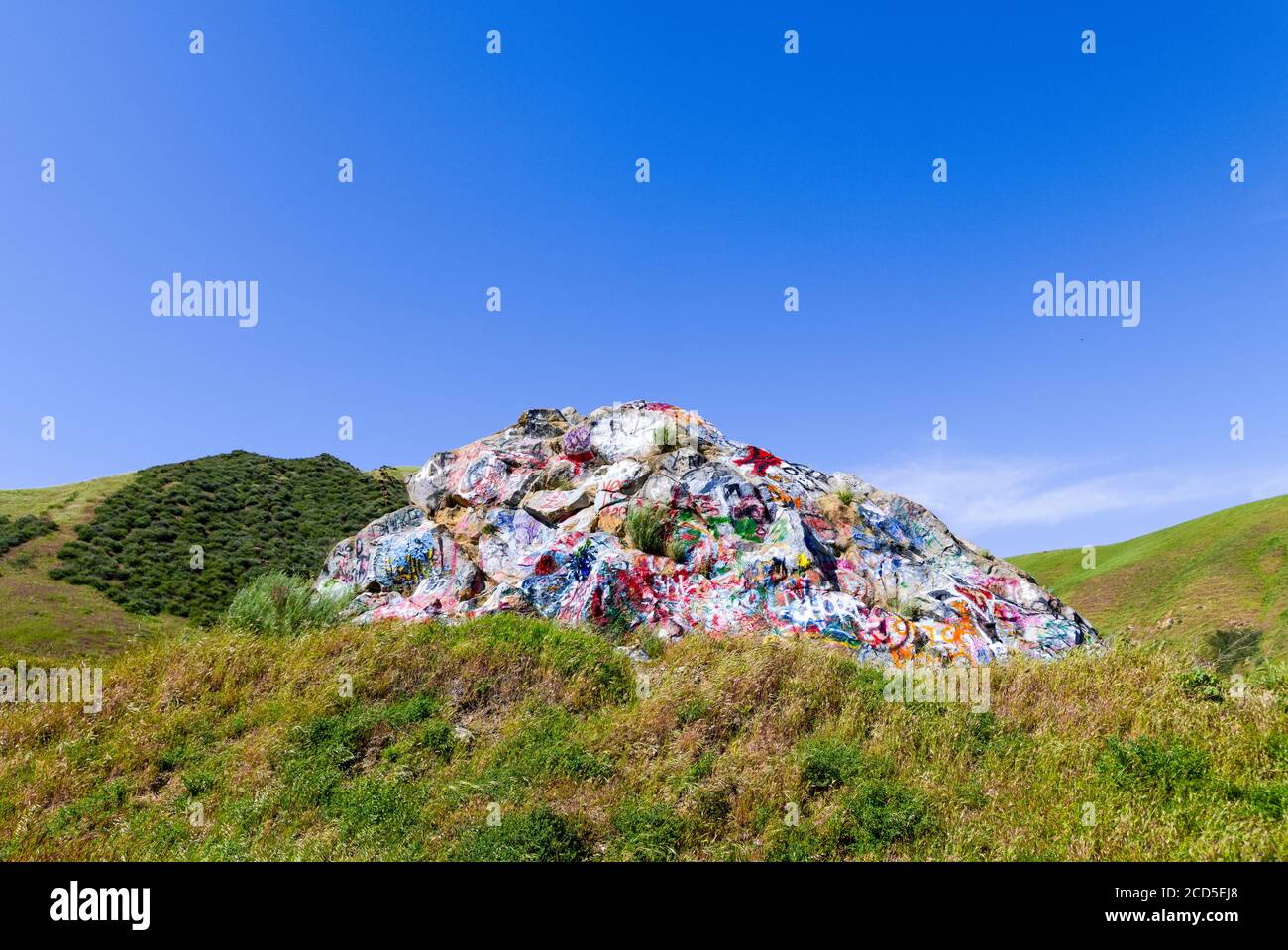 Paesaggio con formazione rocciosa vandalizzato con graffiti e colline ondulate Foto Stock