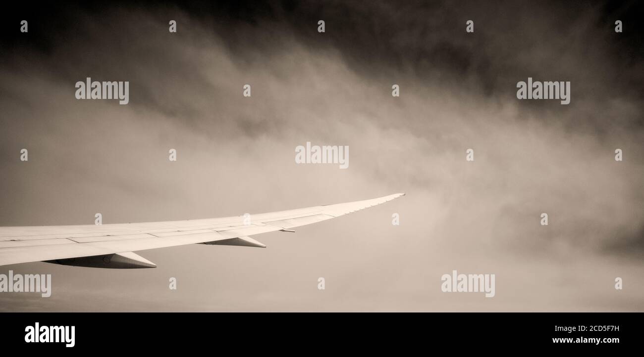 Fotografia in bianco e nero dell'ala dell'aeroplano con le nuvole dentro sfondo Foto Stock