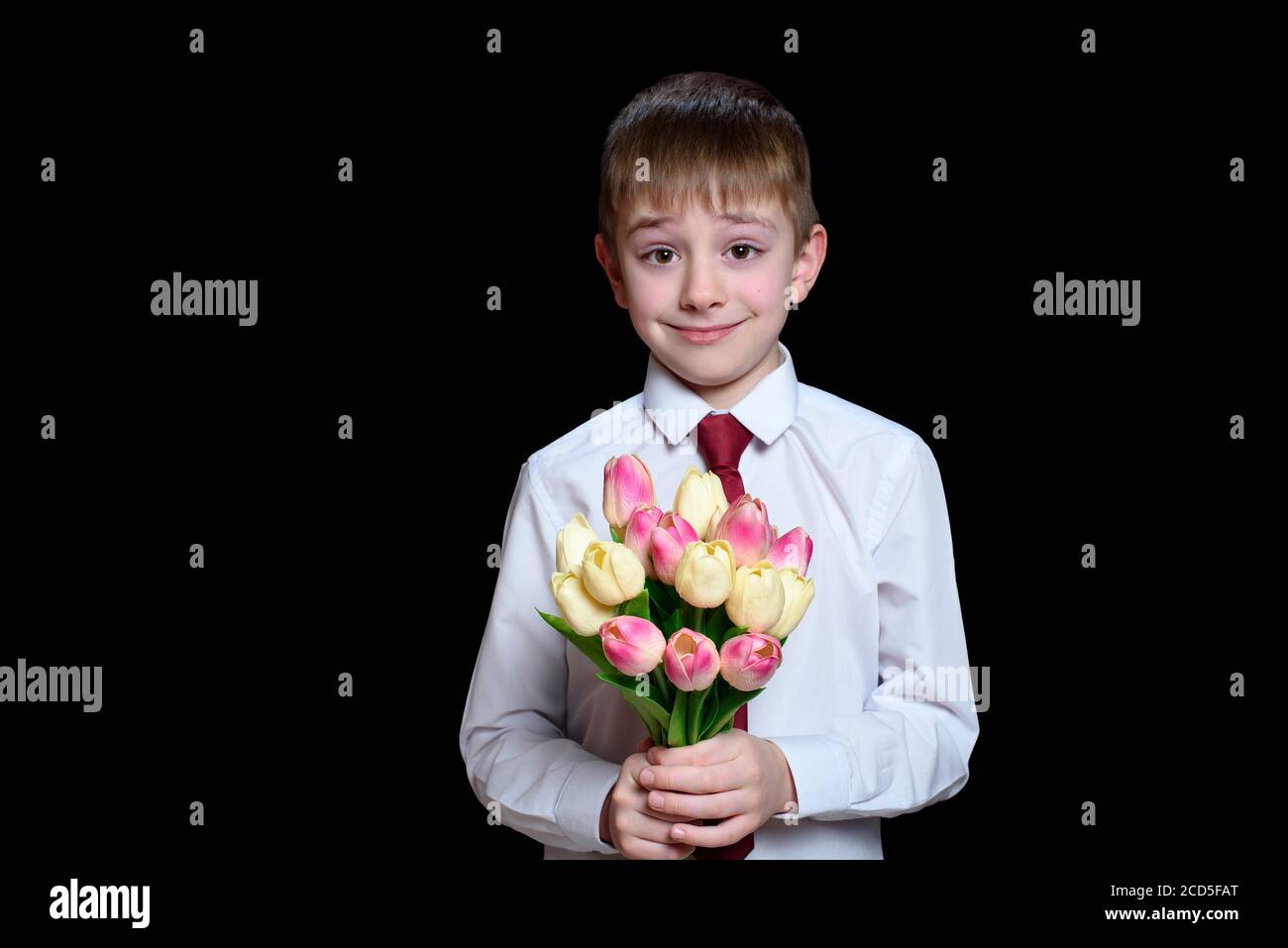 Il ragazzino in camicia bianca dà un bouquet di tulipani. Isolare su sfondo nero Foto Stock