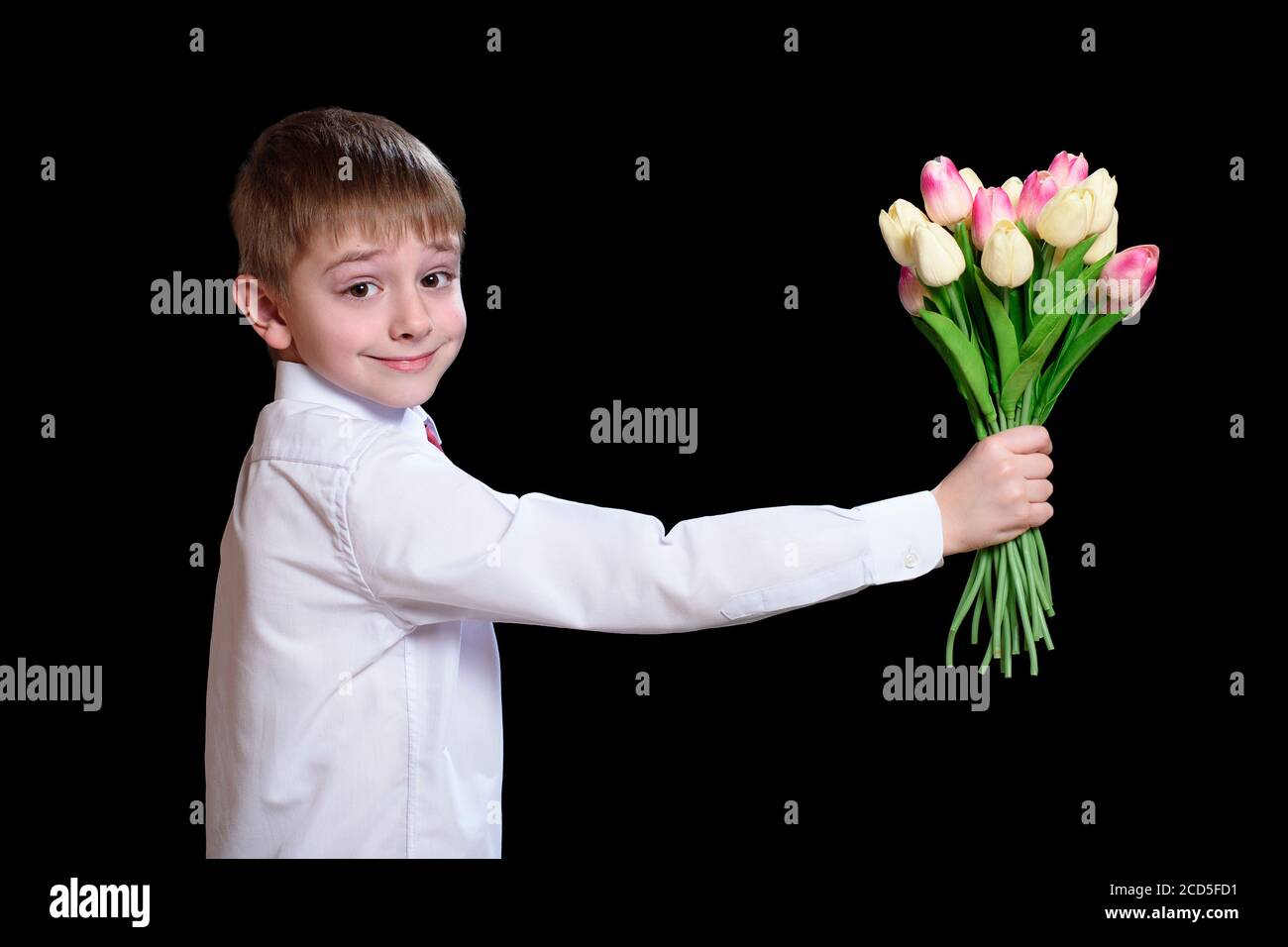 Il ragazzino in camicia bianca dà un bouquet di tulipani. Isolare su sfondo nero Foto Stock