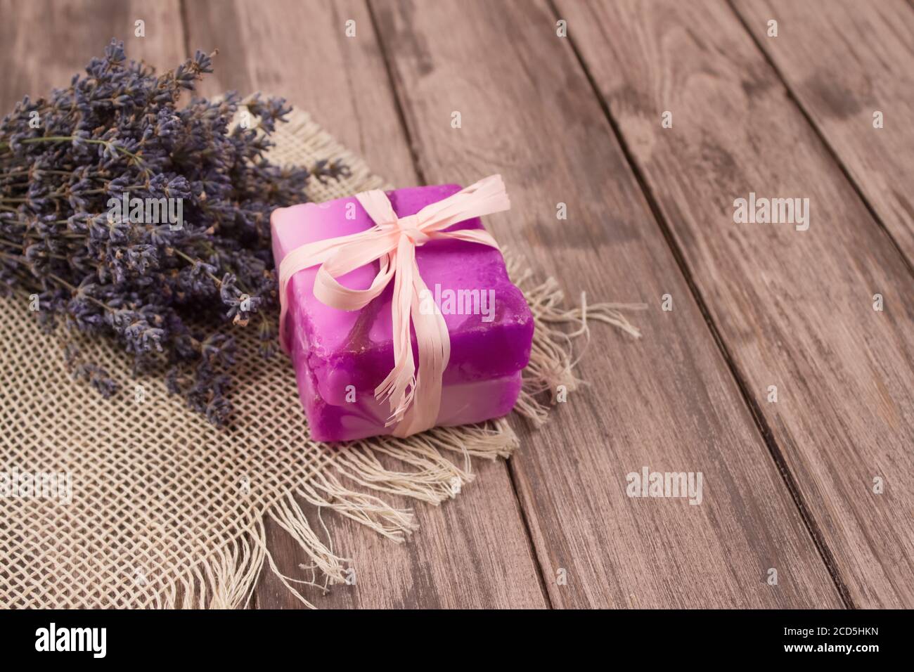Bar di sapone naturale fatto a mano con estratto di lavanda e fiori di lavanda su sfondo naturale di legno con copyspace. Trattamenti benessere in casa. Naturale Foto Stock