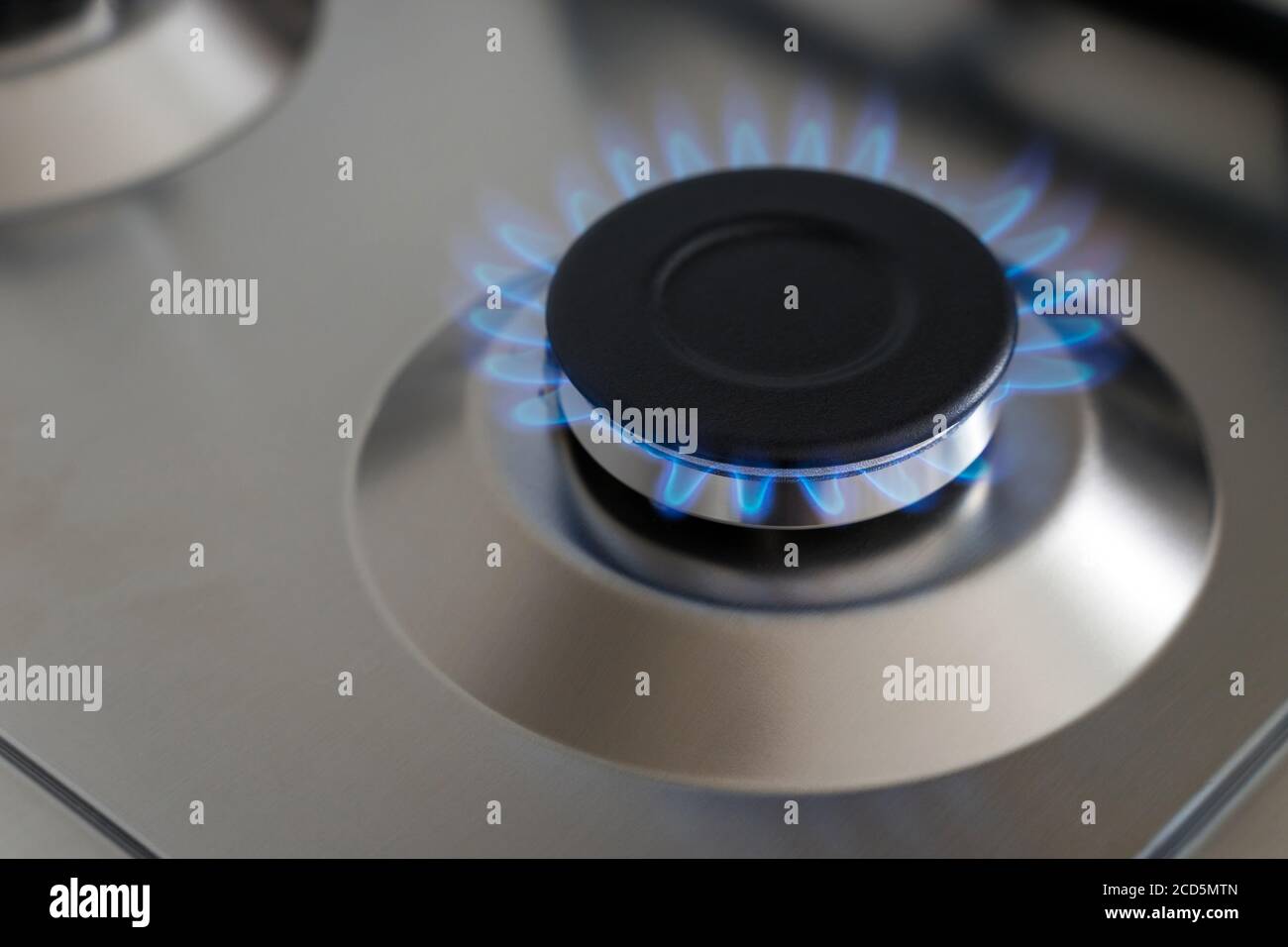 Closeup fiamma blu da un bruciatore di stufa a gas. Superficie cucina in acciaio inox. Foto Stock