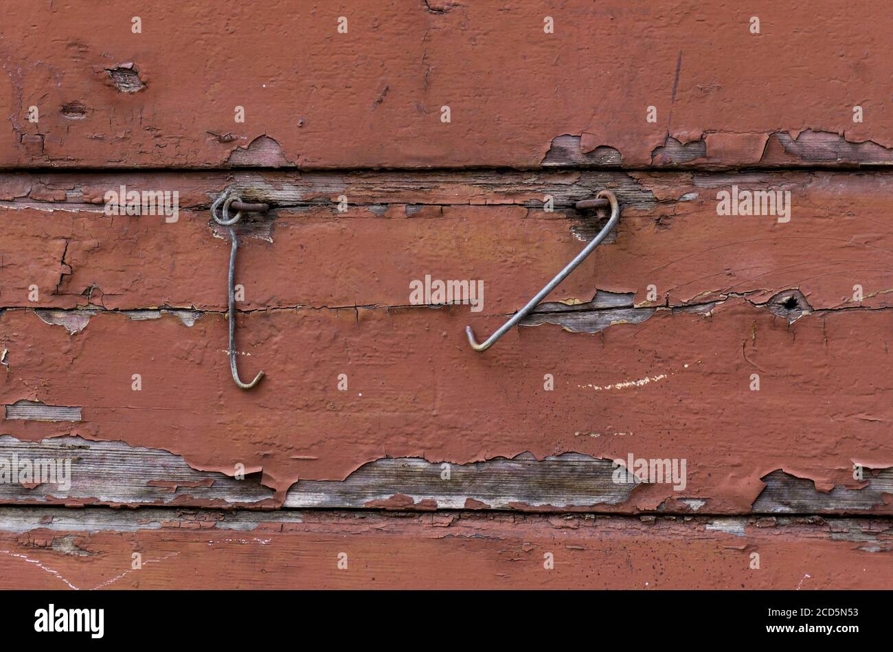 I ganci di metallo dell'otturatore pendono sulla vecchia parete di legno verniciata marrone. Sfondo con struttura in legno, tavole di legno marroni. Foto Stock