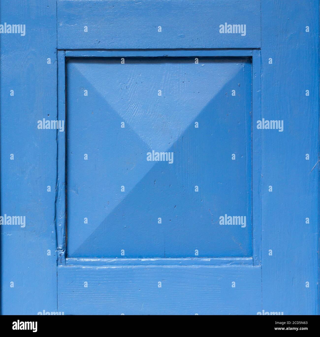 Particolare di una vecchia porta in legno dipinta di blu. Sfondo blu. Cornice quadrata blu. Foto Stock