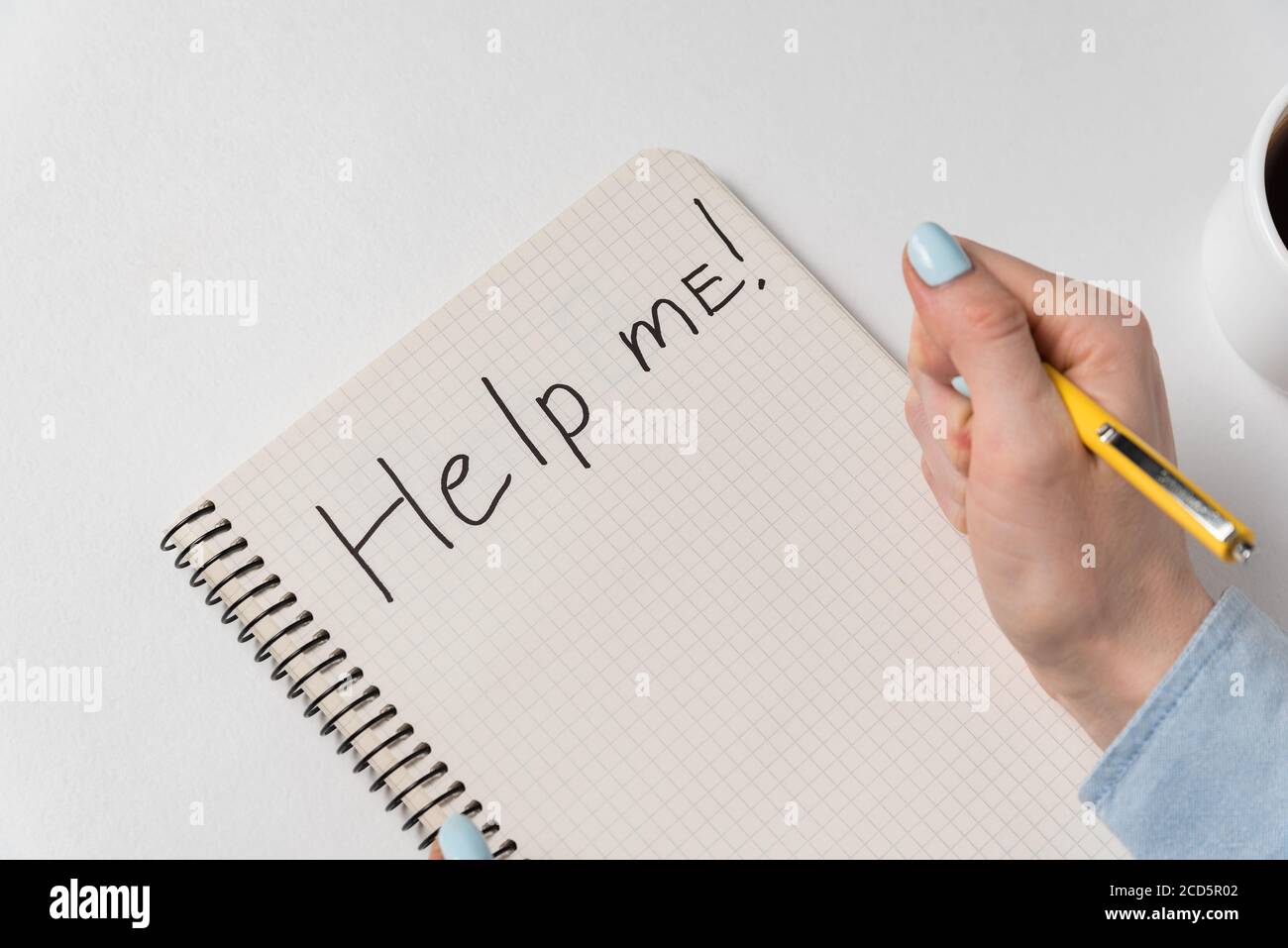 Aiutami a scrivere sul notebook su sfondo bianco. La mano femminile che scrive nel copybook. Foto Stock