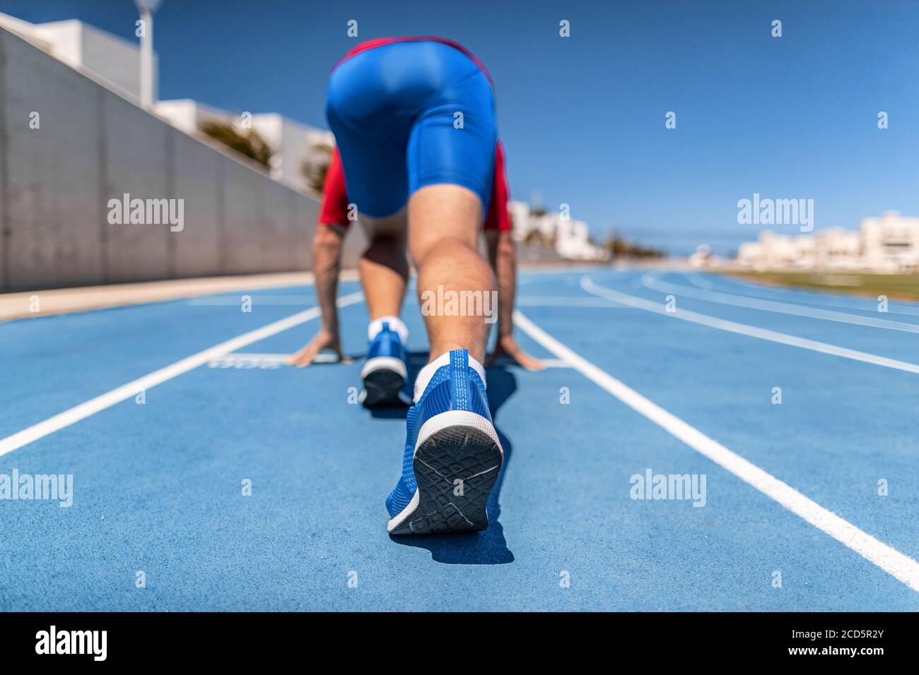 Sprinter alla linea di partenza in attesa di iniziare la gara di corsa in pista e campo fuori stadio. Atleta running all'aperto Foto Stock