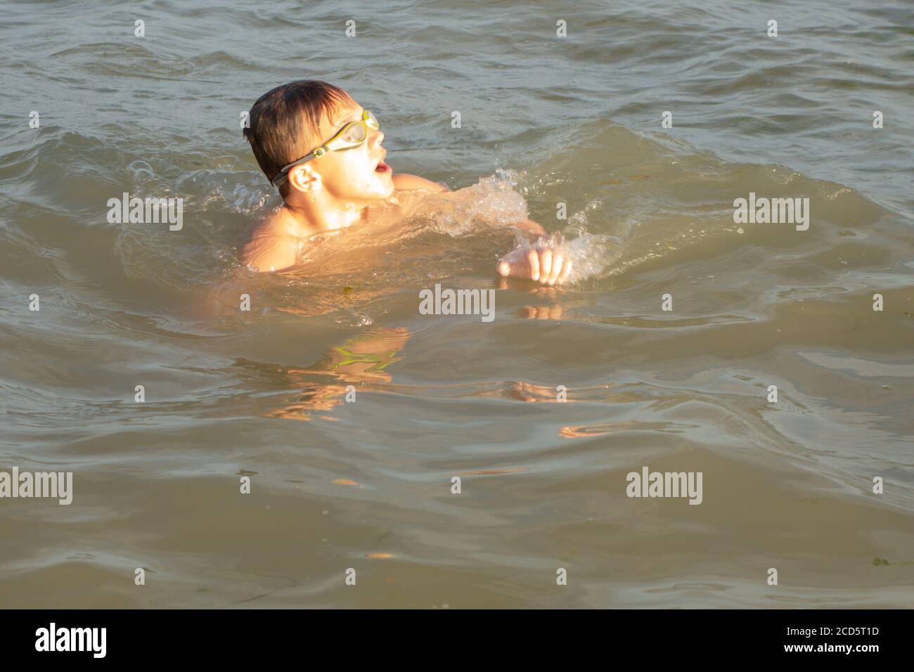 Ragazzo di 10 anni nuota in mare in una giornata di sole. Foto Stock