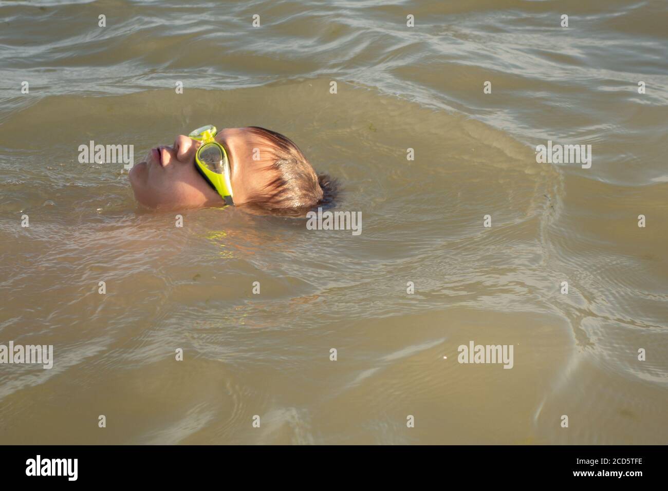 Ragazzo di 10 anni nuota in mare in una giornata di sole. Foto Stock