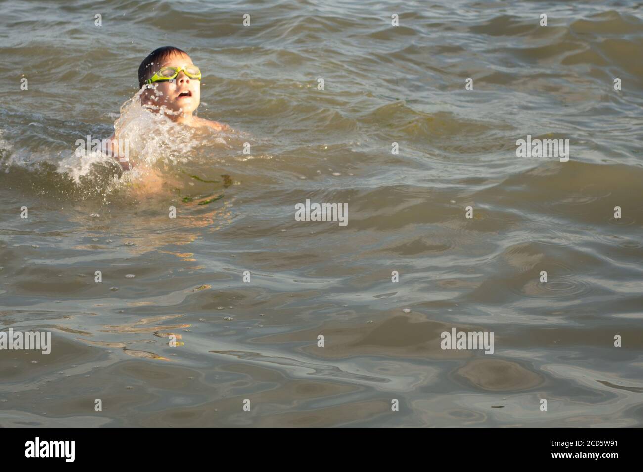 Ragazzo di 10 anni nuota in mare in una giornata di sole. Foto Stock