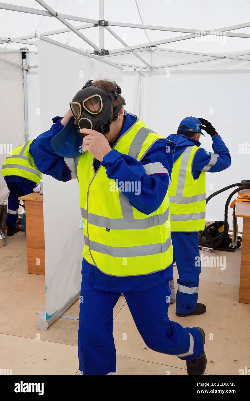 Il lavoratore mette sulla maschera a gas per proteggere contro il gas in emergenza Foto Stock