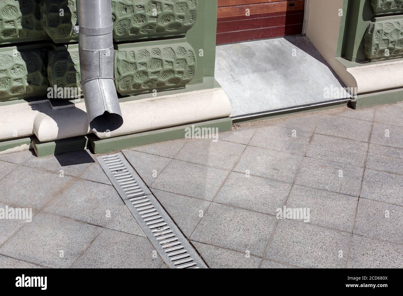 struttura urbanistica discendente su facciata verde edificio con grata di drenaggio di granito grigio marciapiede da piastrelle quadrate con spazio copia, c. Foto Stock struttura urbanistica discendente su facciata verde edificio con grata di drenaggio di granito grigio marciapiede da piastrelle quadrate con spazio copia, c. Foto Stock