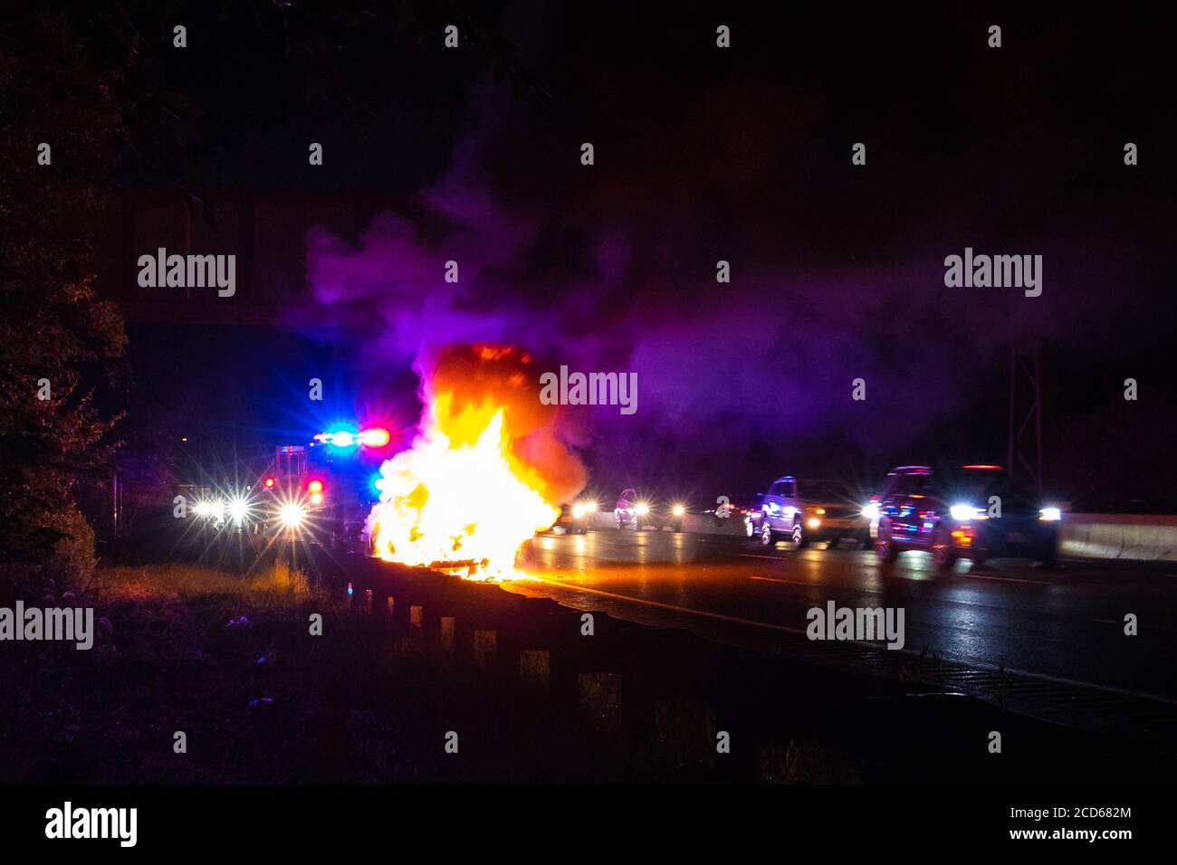 Auto sul fuoco incidente notturno sulla strada con polizia Foto Stock