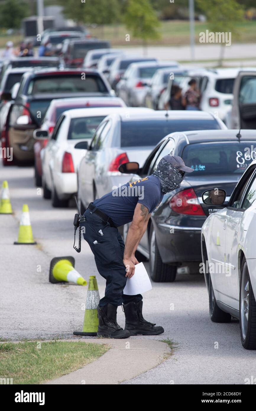 Austin, Texas USA 26 agosto 2020: I vigili del fuoco di Austin si tengono al check-in con i piloti di centinaia di auto provenienti dalla costa orientale del Texas e dalla Louisiana sudoccidentale mentre aspettano in fila presso un centro di evacuazione dell'uragano Laura presso le aree di parcheggio del circuito delle Americhe. Gli autisti che arrivano in anticipo hanno ricevuto buoni per le camere d'hotel. Una volta esauriti, gli autisti sono stati indirizzati ad altri centri di evacuazione a Waco e Dallas. Laura dovrebbe fare la caduta di terra durante la notte come una tempesta di categoria 4 e devastare lungo le coste del Texas e della Louisiana e l'entroterra. Credit: Bob Daemmrich/Alamy Live News Foto Stock