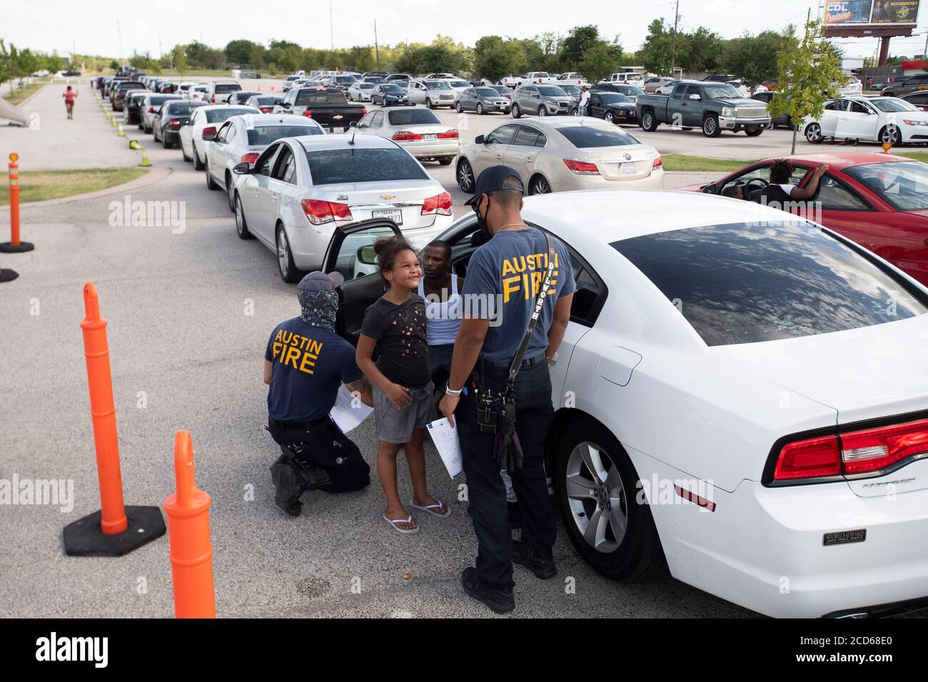 Austin, Texas USA 26 agosto 2020: Centinaia di auto dalla costa orientale del Texas e sud-ovest della Louisiana aspettano in fila un centro di evacuazione dell'uragano Laura presso il circuito delle Americhe. Dopo aver trascorso ore in auto, questa famiglia riceve aria fresca e informazioni dai vigili del fuoco di Austin che hanno assegnato il personale al centro. Laura dovrebbe fare la caduta di terra durante la notte come una tempesta di categoria 4 e devastare lungo le coste del Texas e della Louisiana e l'entroterra. Credit: Bob Daemmrich/Alamy Live News Foto Stock