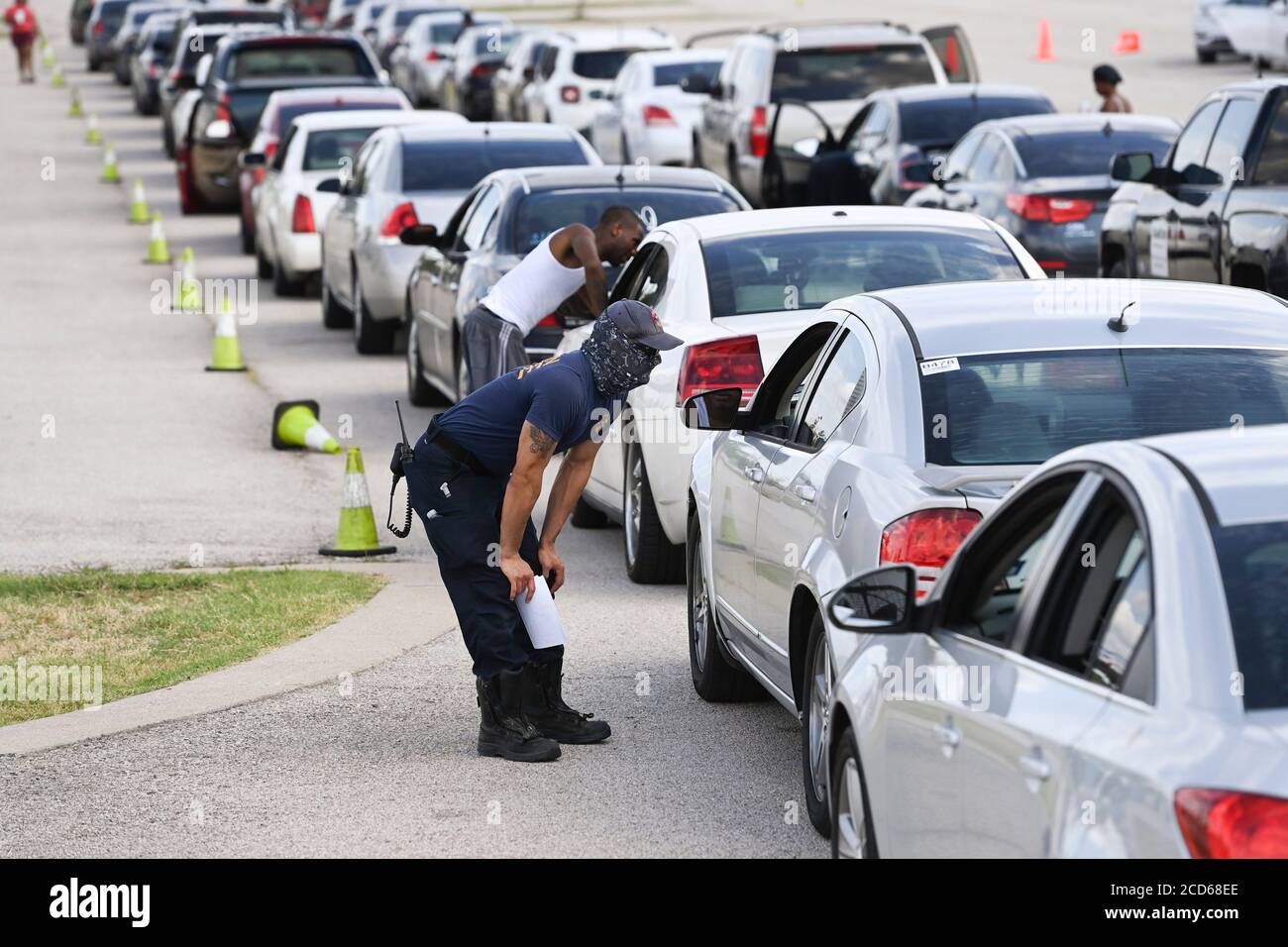 Austin, Texas USA 26 agosto 2020: I vigili del fuoco di Austin si tengono al check-in con i piloti di centinaia di auto provenienti dalla costa orientale del Texas e dalla Louisiana sudoccidentale mentre aspettano in fila presso un centro di evacuazione dell'uragano Laura presso le aree di parcheggio del circuito delle Americhe. Gli autisti che arrivano in anticipo hanno ricevuto buoni per le camere d'hotel. Una volta esauriti, gli autisti sono stati indirizzati ad altri centri di evacuazione a Waco e Dallas. Laura dovrebbe fare la caduta di terra durante la notte come una tempesta di categoria 4 e devastare lungo le coste del Texas e della Louisiana e l'entroterra. Credit: Bob Daemmrich/Alamy Live News Foto Stock