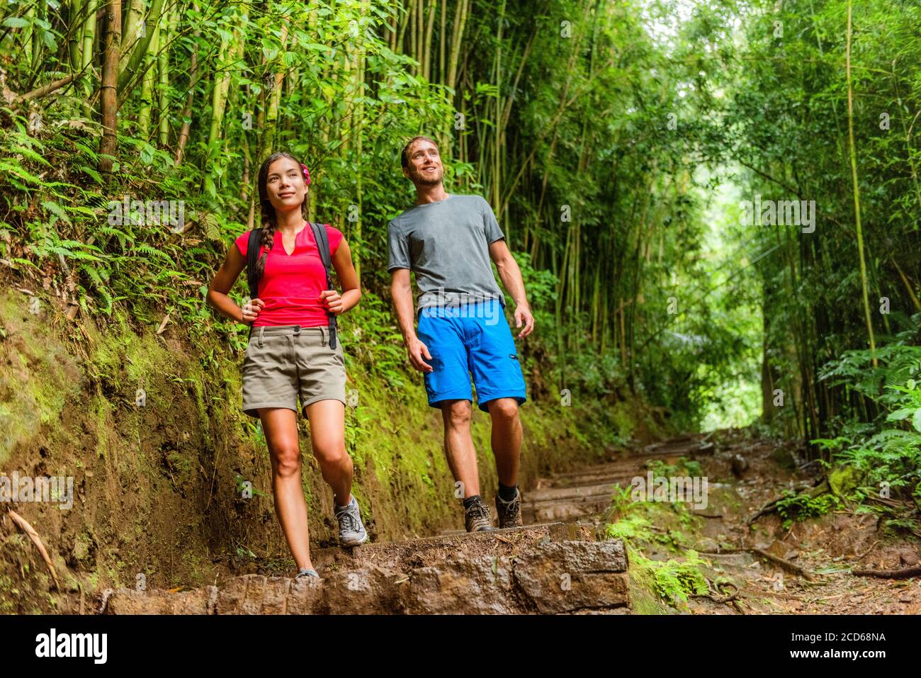 Escursione nella foresta escursionisti escursionisti nel sentiero della foresta pluviale alle Hawaii. Coppia interracial a piedi in avventura di viaggio. Donna asiatica, uomo caucasico stile di vita attivo Foto Stock