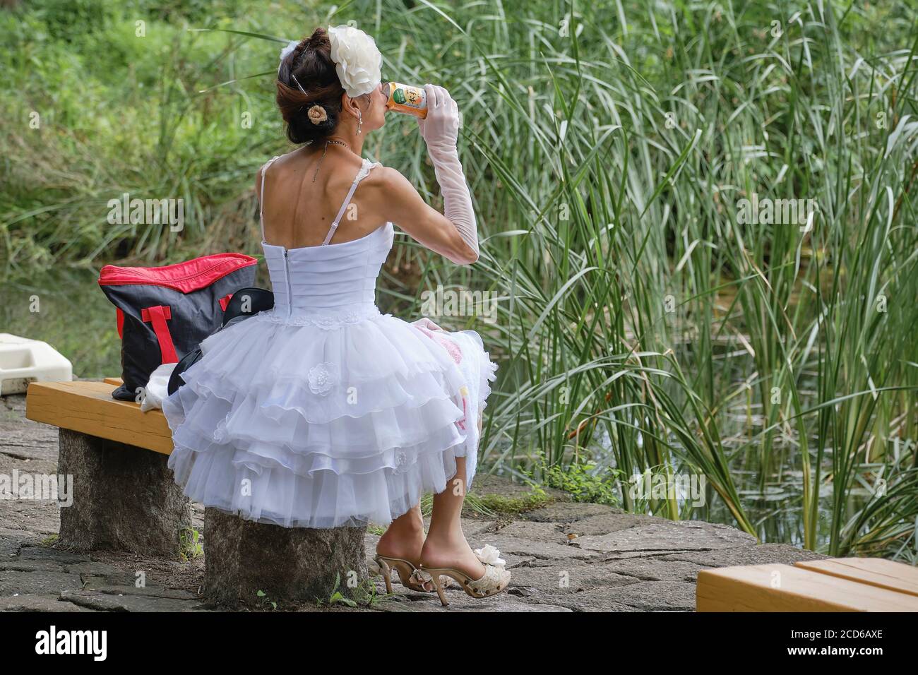 Donna che indossa un abito da sposa e beve una lattina di birra in un parco a Tokyo, Giappone. Foto Stock