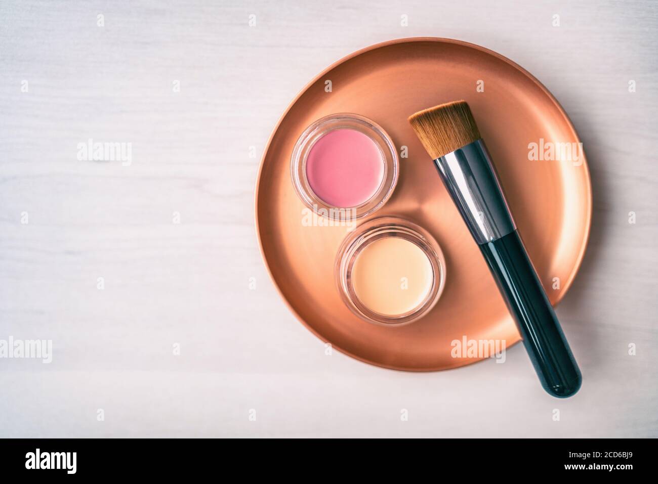 Spazzola per il make-up con base crema e sfumature di colore arrossito. Prodotti di bellezza spazzola per il trucco con vasi di colore rosa e rosso su acciaio inox Foto Stock