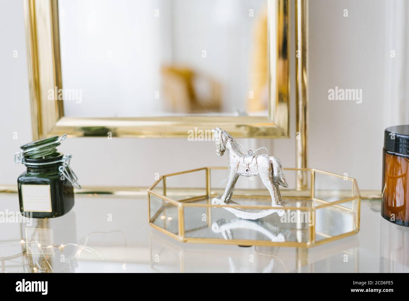 Decorazioni natalizie in camera da letto o in soggiorno sullo scaffale: Souvenir cavallo retrò su un vassoio di vetro e una candela Foto Stock