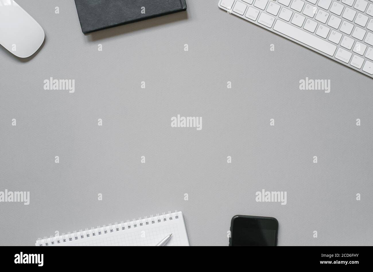 Luogo di lavoro di un lavoratore o freelance tastiera, mouse, alianti e diari, penna a sfera, telefono su sfondo grigio con spazio per la copia. Foto Stock