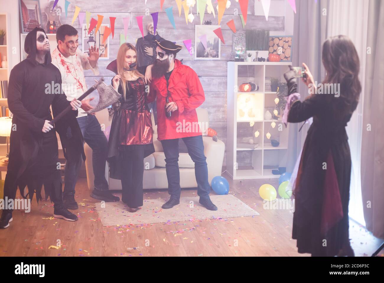 Vista posteriore della strega scattando foto di un gruppo di persone spaventose alla festa di Halloween. Foto Stock