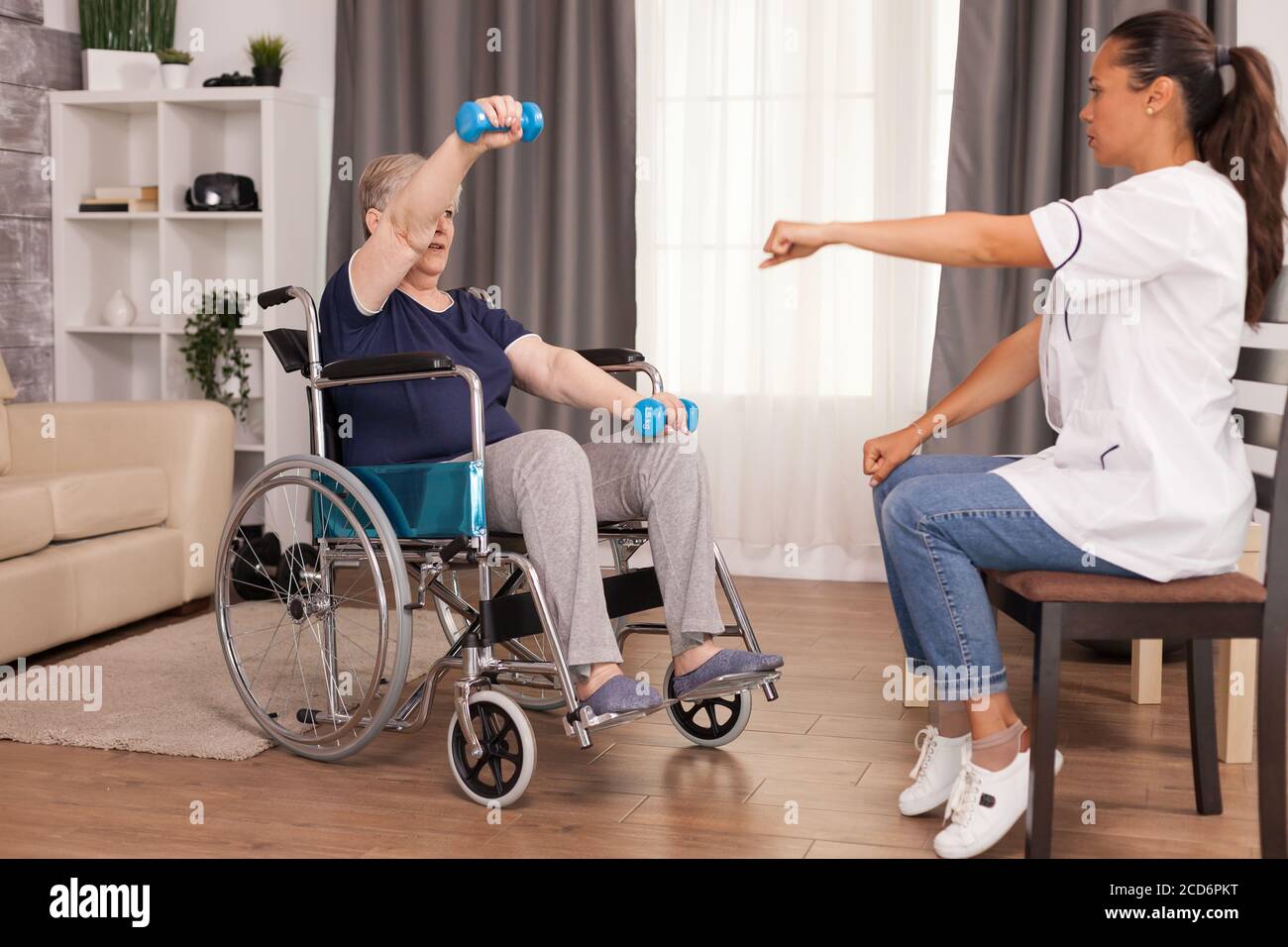 Donna anziana in sedia a rotelle che fa riabilitazione fisica con il medico. Disabile anziano ricoverato infermiera di aiuto professionale, cura di casa di riposo e riabilitazione Foto Stock