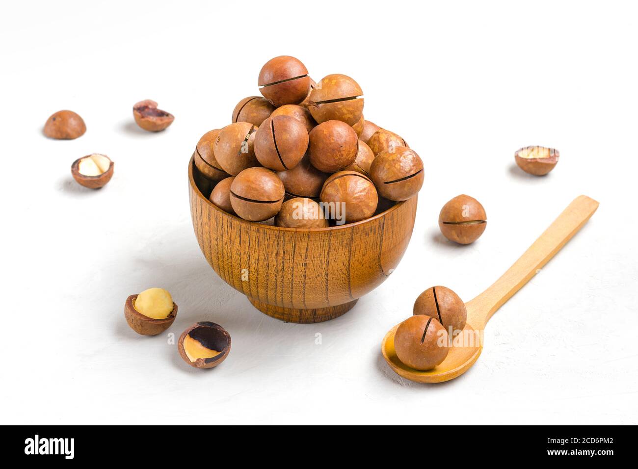 noci di macadamia naturale organica in ciotola di legno su cemento grigio Sfondo Flat Lay Top vista snack sani noci con essenziale Olio ricco di vitamine B. Foto Stock