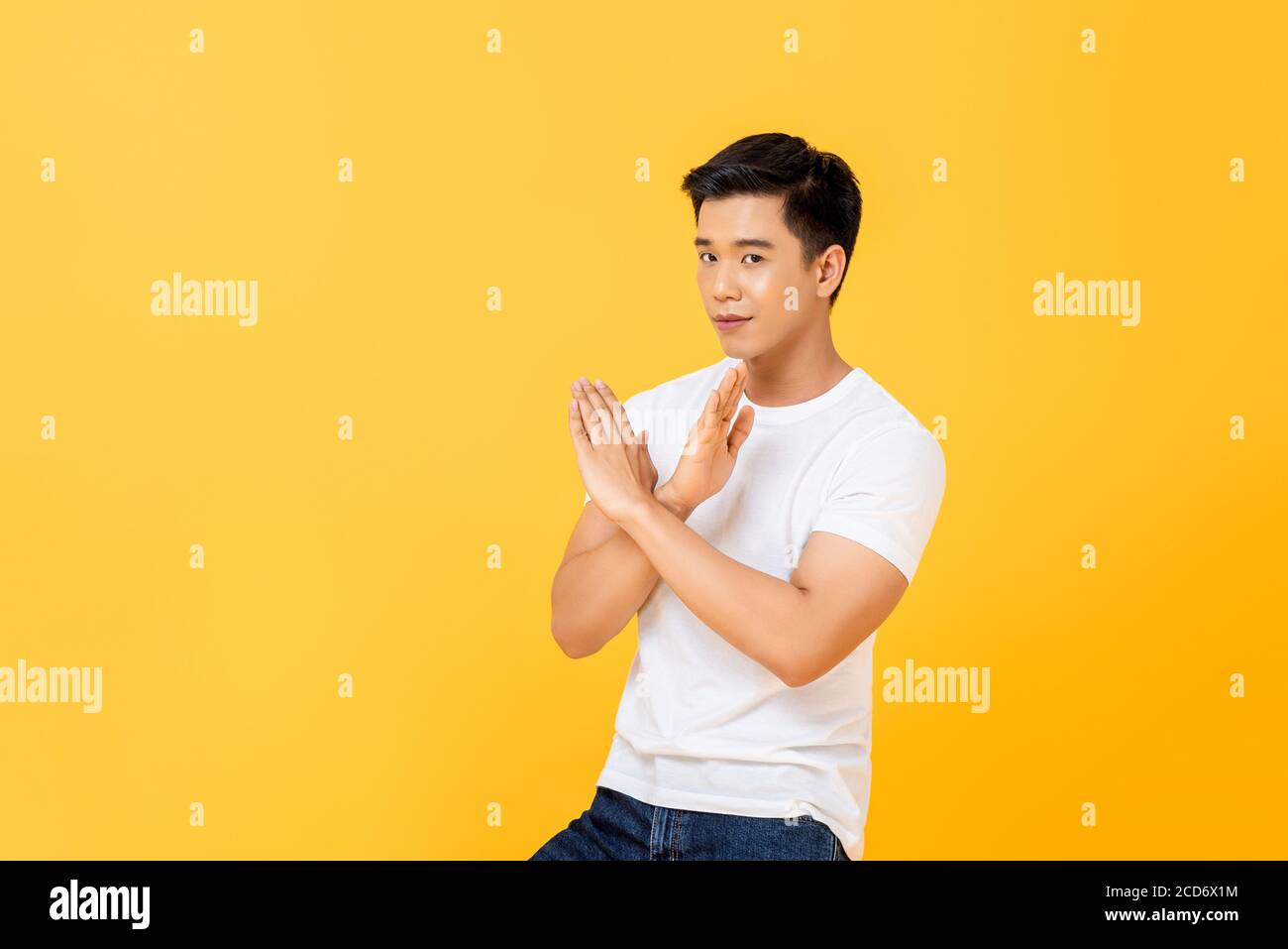 Ritratto di giovane bell'uomo asiatico che mostra disaccordo facendo x movimento incrociato della mano su sfondo giallo isolato dello studio Foto Stock
