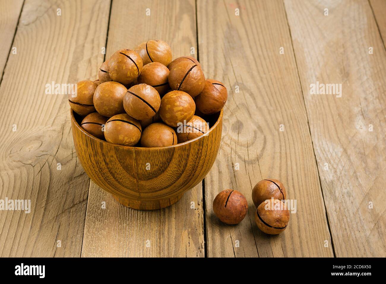 Noci di macadamia naturale organica in ciotola su tavola di legno piatto Vista dall'alto i noci di snack sani contengono l'olio essenziale ricco di vitamine B e PP, molto Foto Stock