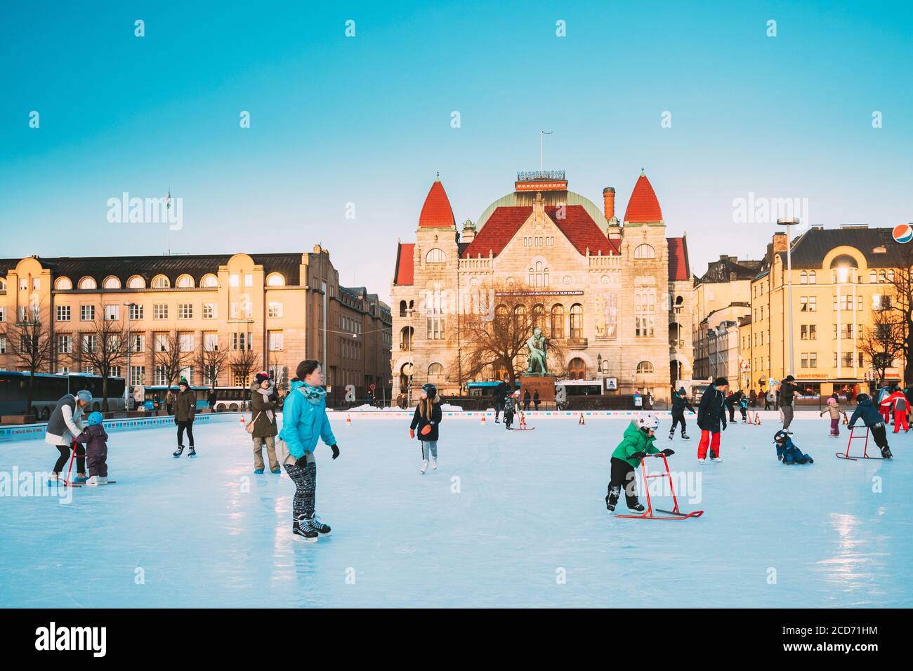 Helsinki, Finlandia. Bambini che pattina sulla pista di pattinaggio su Railway Square sullo sfondo del Teatro Nazionale Finlandese nel giorno di sole invernale Foto Stock