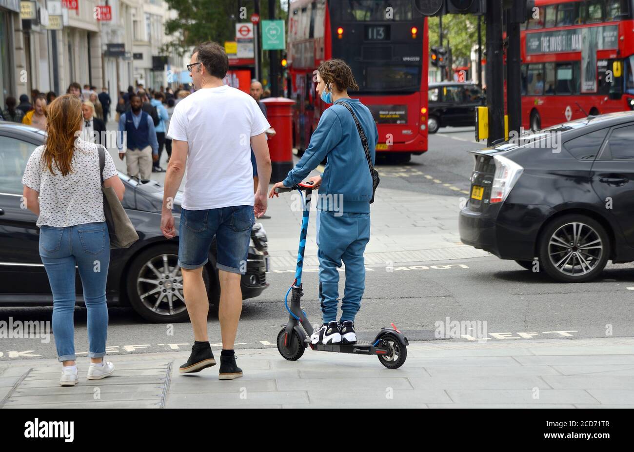 Londra, Inghilterra, Regno Unito. Giovane uomo su uno scooter elettrico in un passaggio pedonale sul marciapiede in Oxford Street Foto Stock