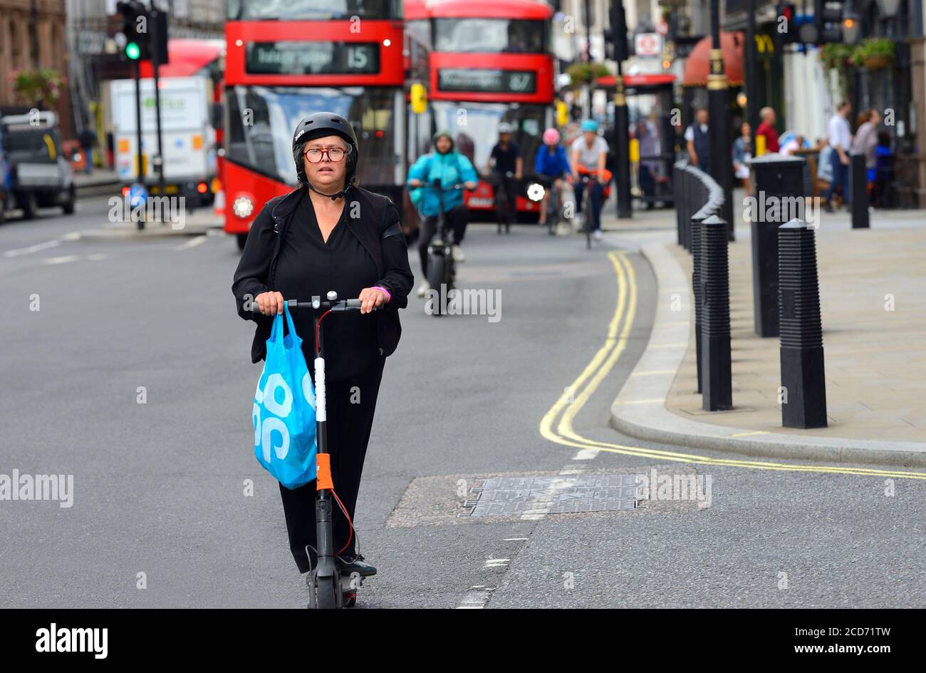 Londra, Inghilterra, Regno Unito. Donna con shopping su uno scooter elettrico a Whitehall Foto Stock