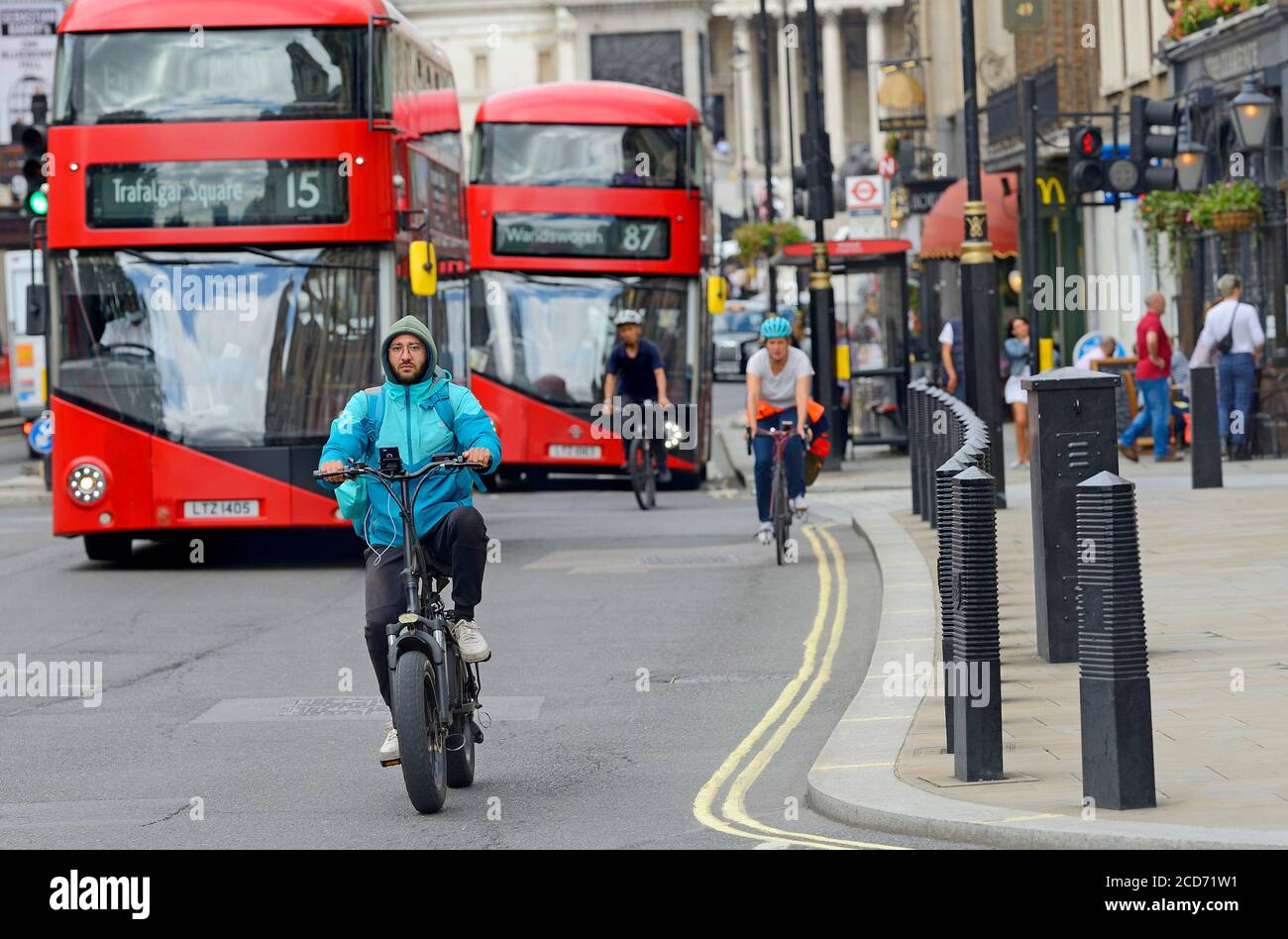 Londra, Inghilterra, Regno Unito. Uomo in bicicletta elettrica a Whitehall, Westminster - autobus e altri ciclisti dietro Foto Stock
