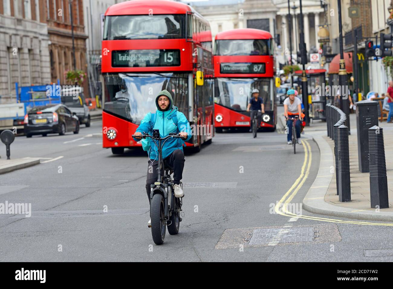 Londra, Inghilterra, Regno Unito. Uomo in bicicletta elettrica a Whitehall, Westminster - autobus e altri ciclisti dietro Foto Stock