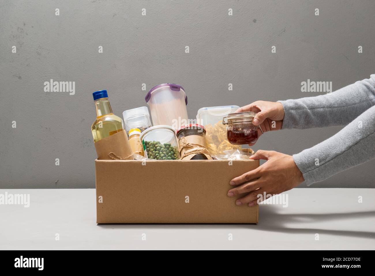 La gente fa fuori i prodotti della scatola isolata su grigio Foto Stock