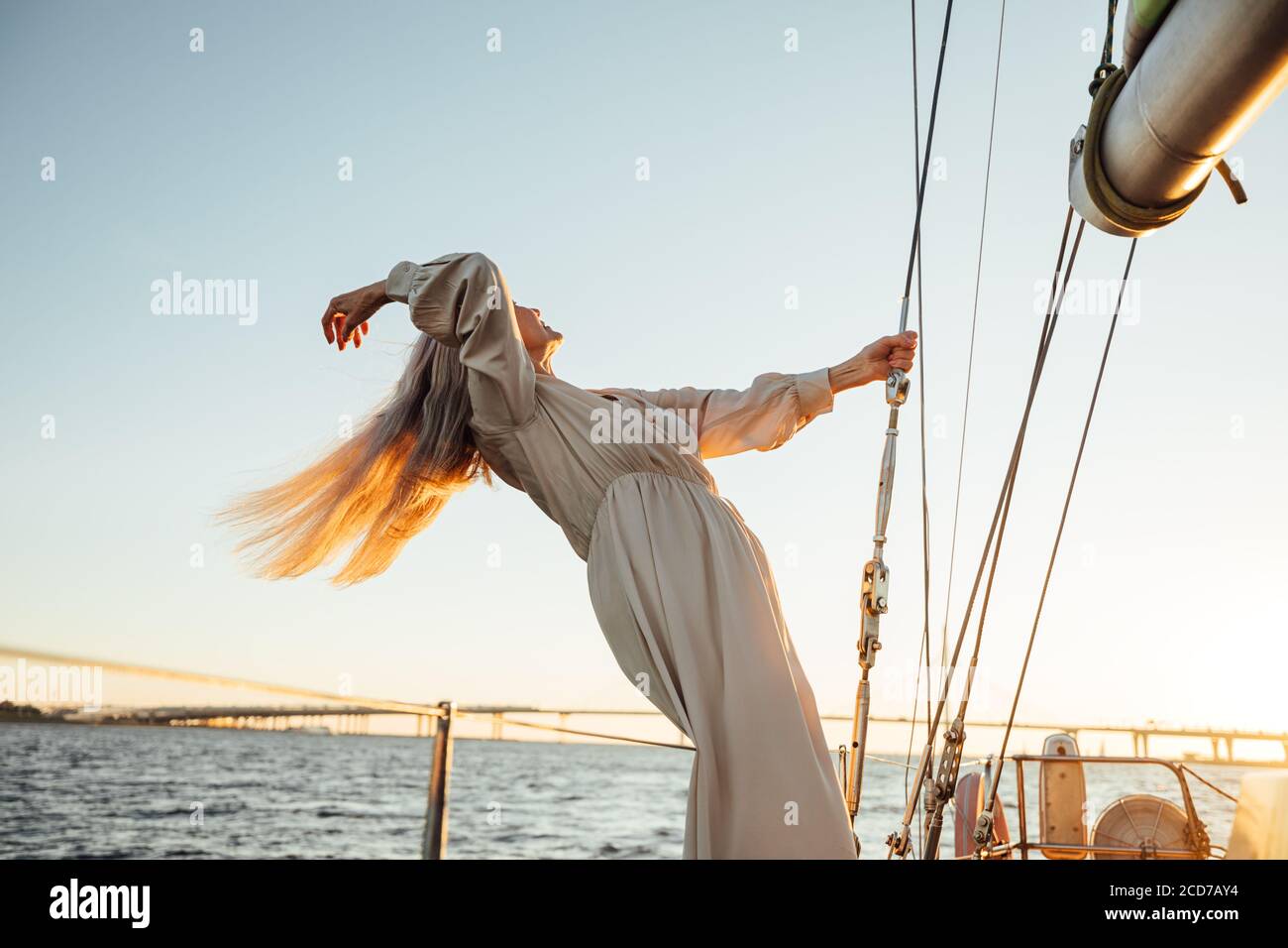 Elegante donna matura con lunghi capelli in piedi su un privato yacht e godersi un tramonto Foto Stock
