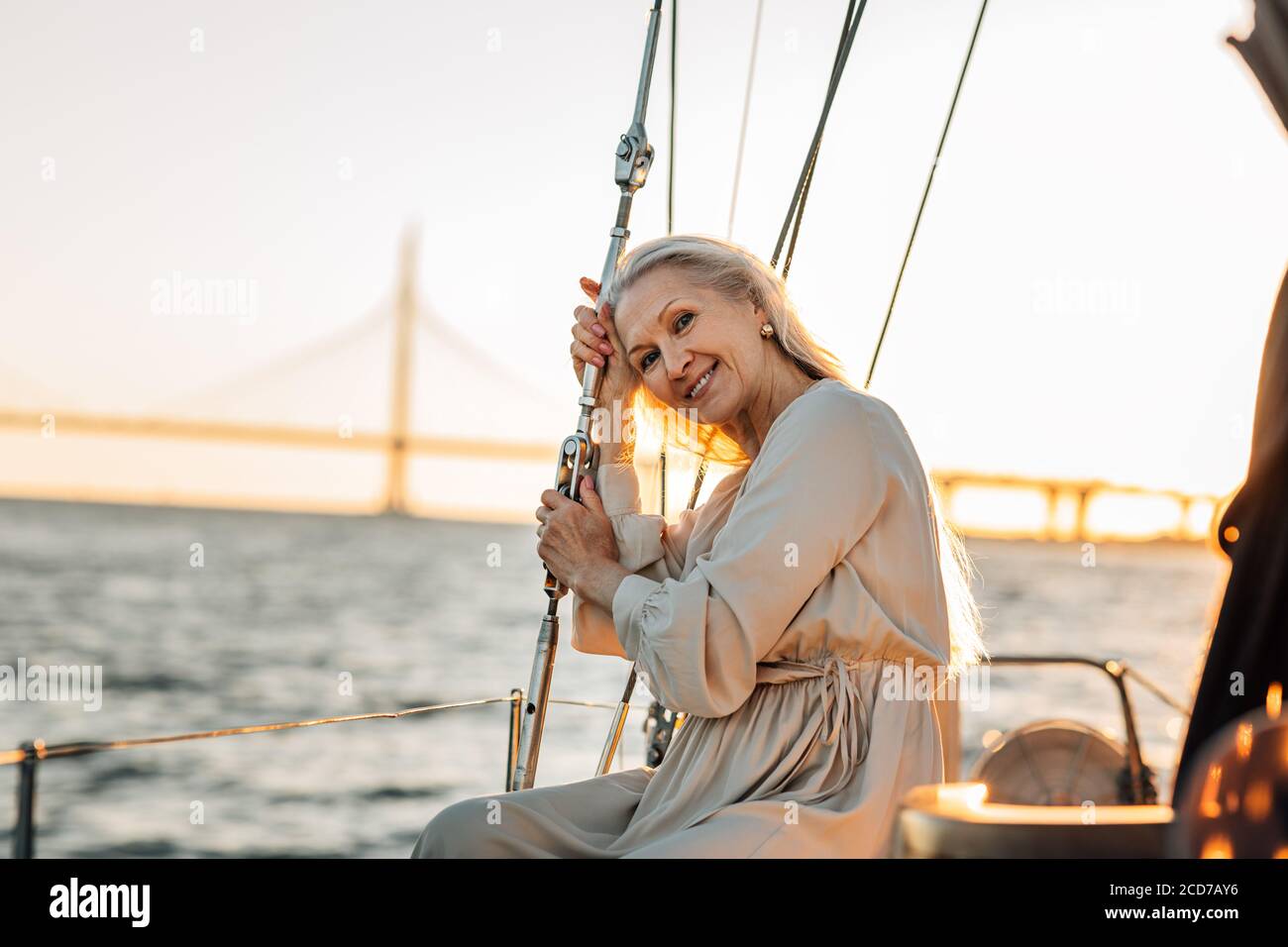 Elegante donna matura seduta su un ponte yacht e guardando una fotocamera Foto Stock
