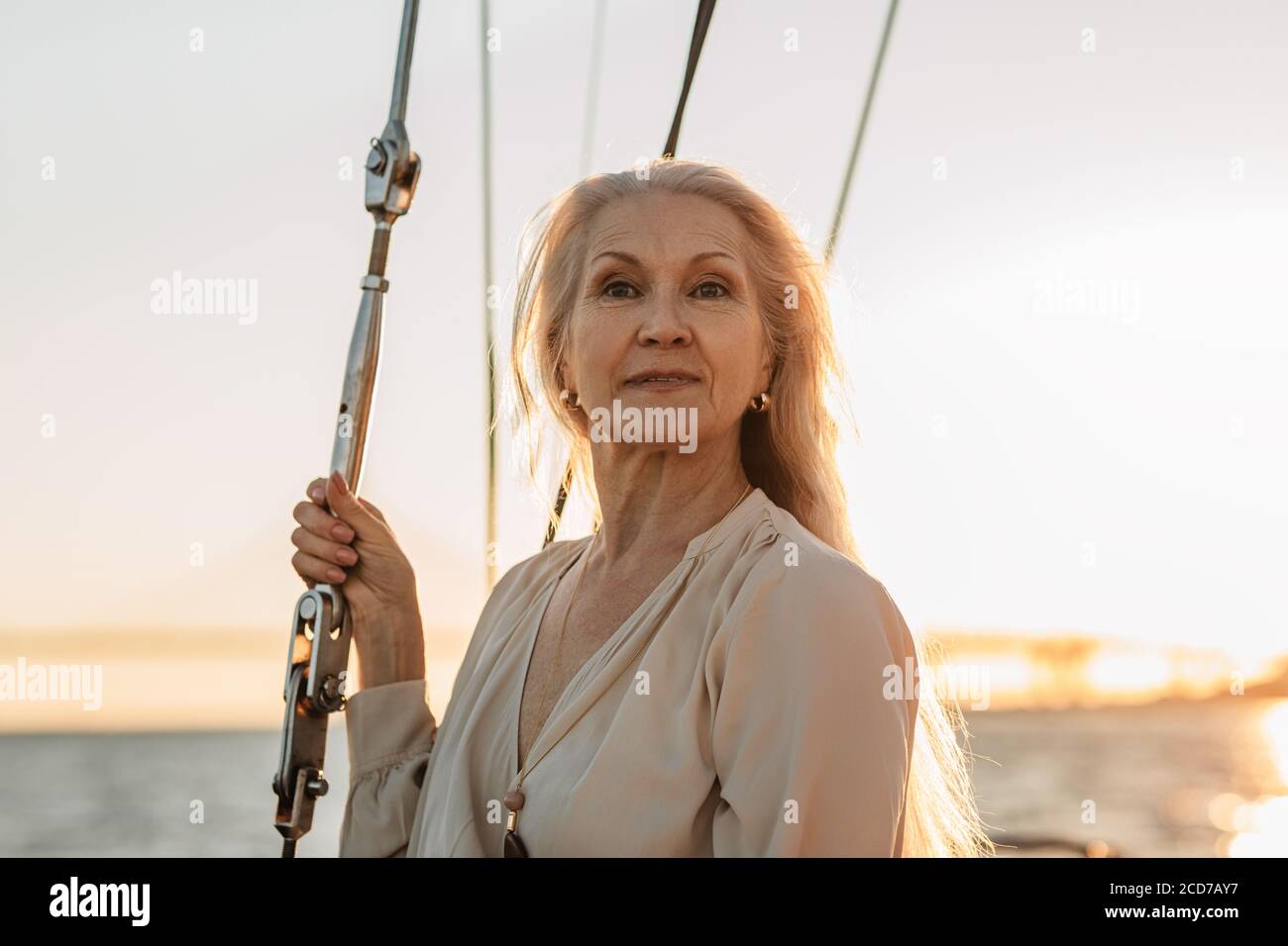 Ritratto di elegante donna matura in piedi su yacht in casual e guardando via Foto Stock