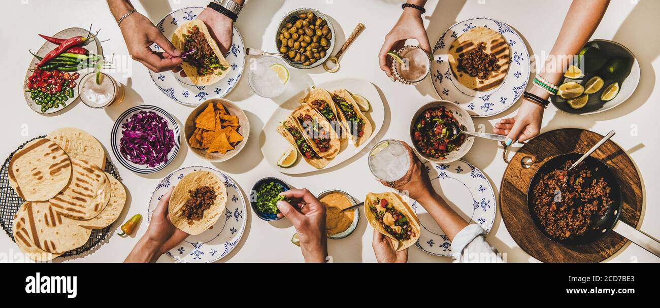 Amici che hanno una cena Taco in stile messicano con birra e spuntini Foto Stock