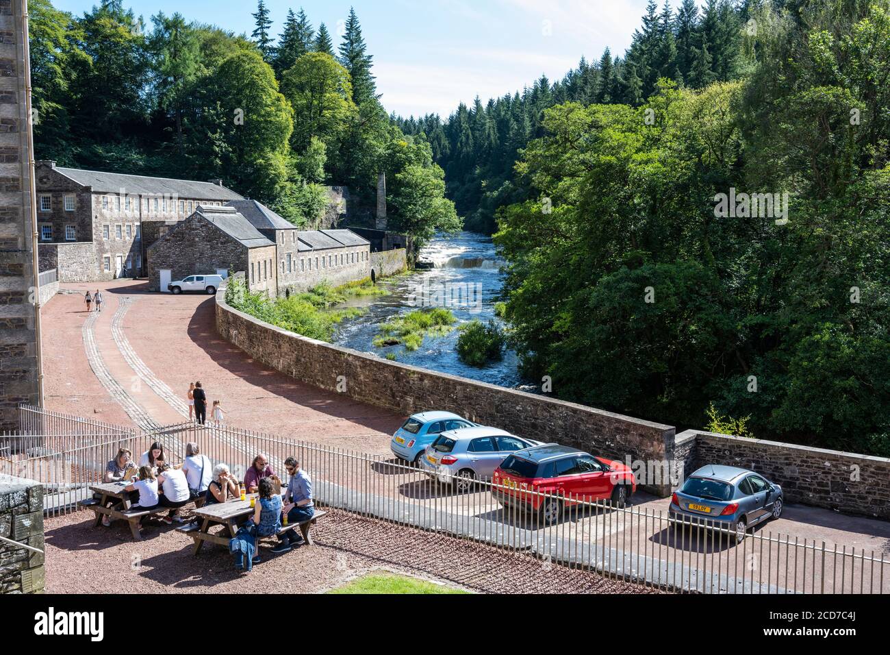 I visitatori potranno godersi il sole estivo al New Lanark, sito patrimonio dell'umanità, a New Lanark, Lanarkshire, Scozia, Regno Unito Foto Stock