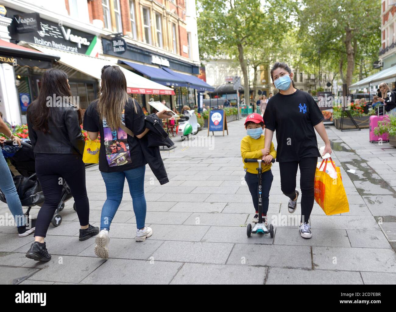 Londra, Inghilterra, Regno Unito. Madre e figlio asiatici su uno scooter a Chinatown durante la pandemia COVID, agosto 2020 Foto Stock